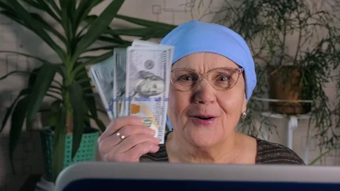 An elderly woman uses a laptop to make money on the Internet. Stock Footage