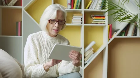 Elderly woman using a computer tablet, looking at the screen, elderly older Stock Footage 144102169
