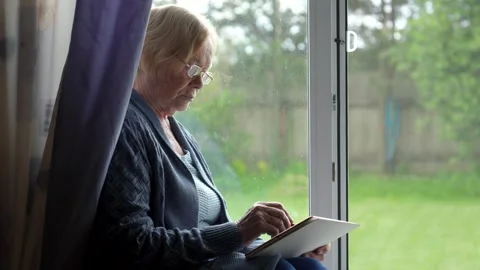 Elderly woman using digital tablet near window Stock Footage 312707105