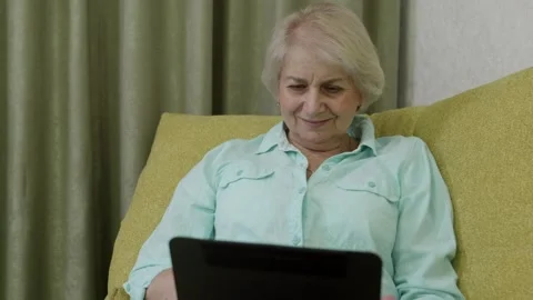 Elderly woman using laptop computer on comfortable sofa Stock Footage 321856045
