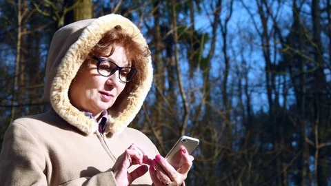 Elderly Woman Using Smartphone In Spring Forest Stock Footage