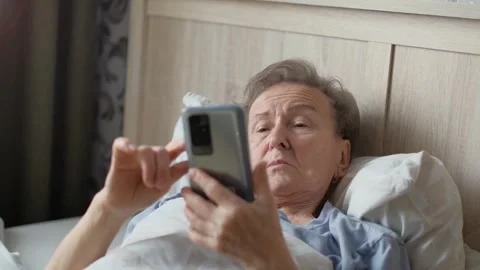 Elderly woman using smartphone while lying in bed at home Stock Footage 285892515