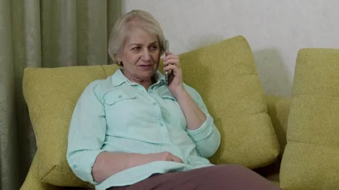 Elderly woman using smartphone while sitting on sofa Stock Footage 321856194