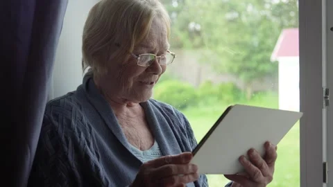 Elderly woman using tablet computer near window Stock Footage 312206036