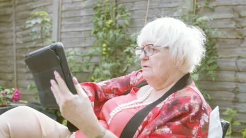 Elderly Woman using tablet device swiping, tapping, smiling and enjoying Stock Footage 139443518
