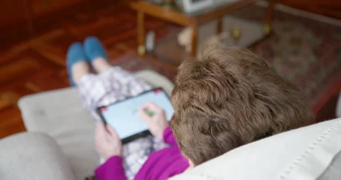 Elderly woman using a tablet on a sofa: Stock Footage 337220979