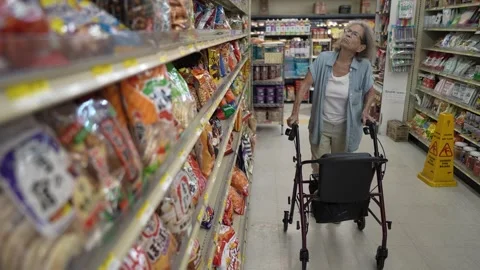 Elderly Woman Using Walker While Grocery Shopping in a Supermarket Aisle Stock Footage 313634133