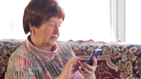 An elderly woman writes a text message on her mobile phone. She carefully Stock Footage 74939151