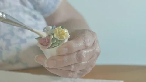 Elderly woman's hands brushing dust off tiny ceramic flowers. Not B&amp;W Vidéo 72739165