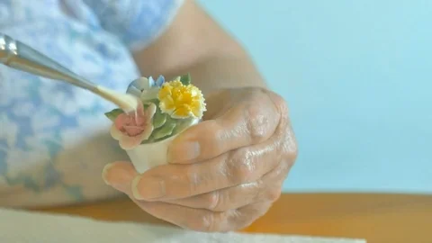 Elderly womans hands brushing dust off tiny ceramic flowers. Color corrected V. Vidéo 72745546