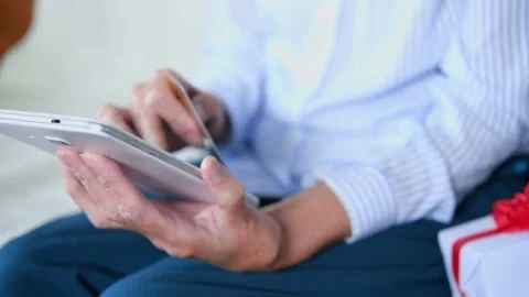 Elderly womans hands closeup using tablet holding credit card buy on internet Stock Footage 159786130