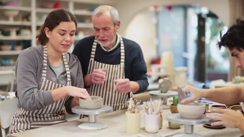 Eldery man helping young guy sculpting ceramic piece Stock Footage 344773959