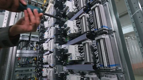 Electircian installing circuit breakers in electrical fuse box at the industrial Stock Footage 73600393