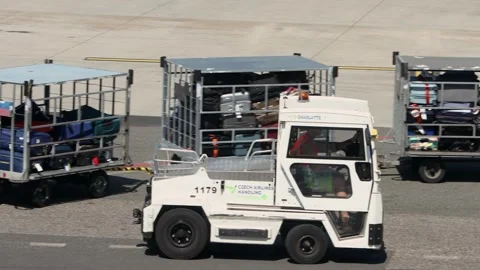 Electric baggage tractor driving on airport apron with luggage carts Stock Footage 340331653