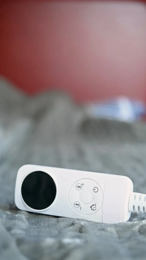 Electric blanket with controller with a sleeping people on the background at Stock Footage 219606435