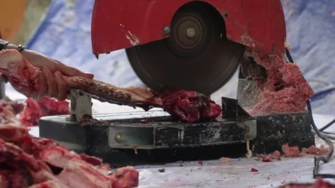 An electric bone saw machine chopping thick beef bones and raw ribs during Islam Stock-Footage 338046376