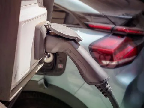 Electric car charging cable plug connected to city charging station Stock Photos