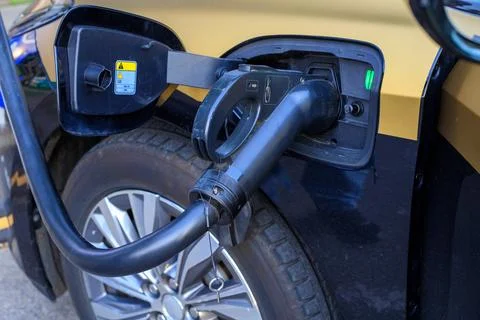 Electric car charging process close up view, EV black connector plugged int.. Stock Photos