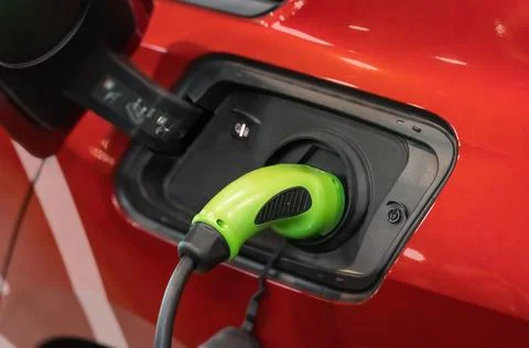 Electric car (EV) is charging in socket with cable. Stock-Fotos