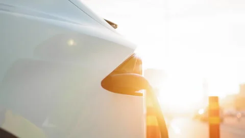 Electric car with plug cord connected to charging port at outdoors EV station Stock Footage 245257393