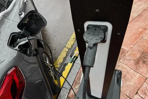 Electric car on a rainy day connected to charging cable Foto stock