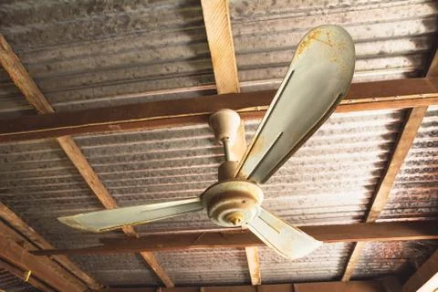 Electric ceiling fan, old rusty ceiling fan on rusty on roof in old house. Stock Photos