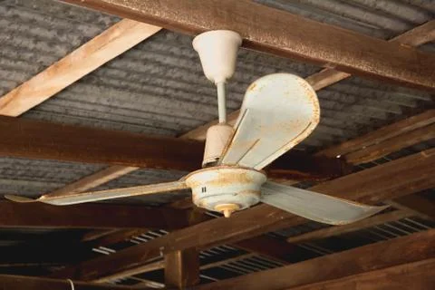 Electric ceiling fan, old rusty ceiling fan on rusty on roof in old house. Stock Photos