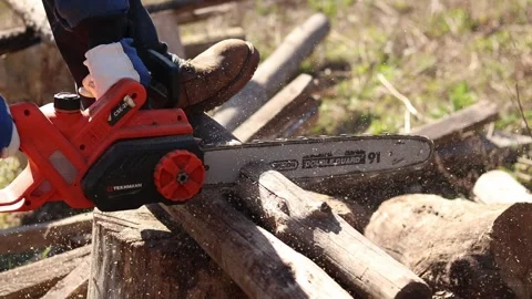 Electric chainsaw in operation. Tekhmann brand tool with Oregon bar Stock Footage 332853494