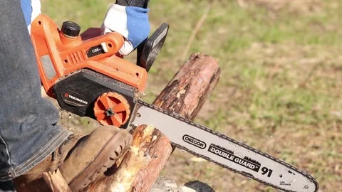 Electric chainsaw in operation. Tekhmann brand tool with Oregon bar Stock Footage 332853601