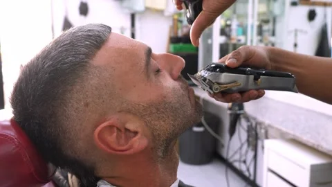 Electric clipper beard shaping by barber in professional salon Stock Footage 318134845
