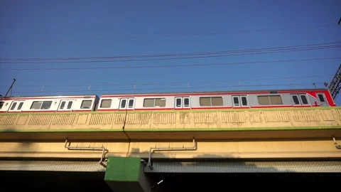Electric commuter train (KRL) passing over an elevated railway flyover bridge Stock Footage 339912975