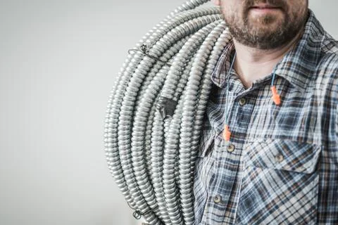 Electric Construction Worker with Conduit Pipe on His Shoulder 库存照片
