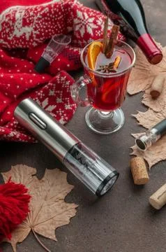 Electric corkscrew on a brown background. Next is a glass of mulled wine. Win Stock Photos