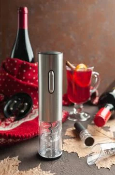 Electric corkscrew on a brown background. Next is a glass of mulled wine. Win Stock Photos