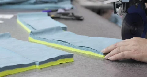 Electric cutter Fabric Machine. Hands of a person cutting fabric in a Sewing Stock Footage 157365526