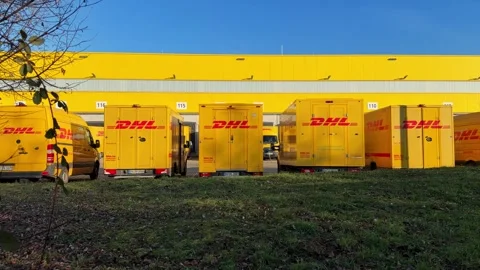 Electric delivery vehicles of German postal service charging at logistics center Stock Footage 325058267