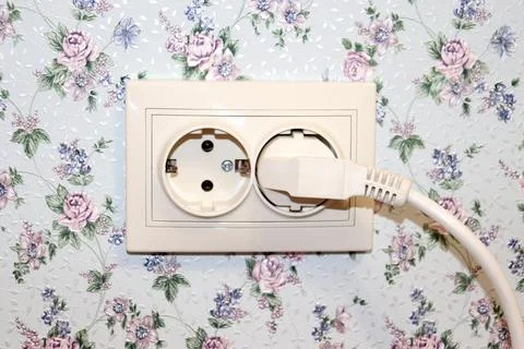 Electric double socket with electric plug on the wall of the room Stock Photos