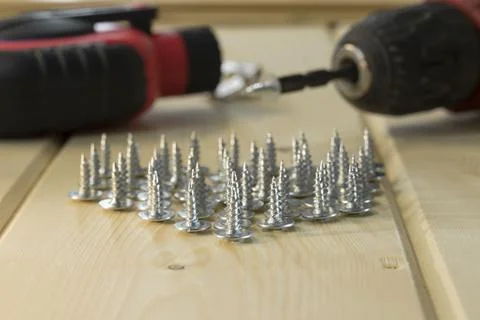 Electric drill with drill bits, screws on wooden background. Bunch of screws  스톡 사진