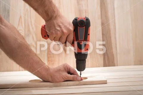 Electric drill screwdriver in male hand. Tightening screw, processing workpie Stock Photos