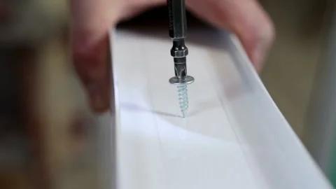 An electric drill screws a self-tapping screw into a window frame Stock Footage 150395975