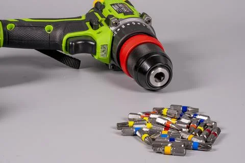 Electric drill with various drill bits on a gray surface close up Stock Photos