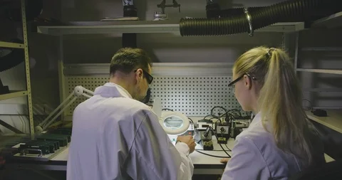 Electric engineer teaching young apprentice soldering microchips in workshop Stock Footage 112064738