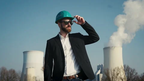 Electric engineer wearing helmet and suit in front of coal fired power station Stock Footage 209315123