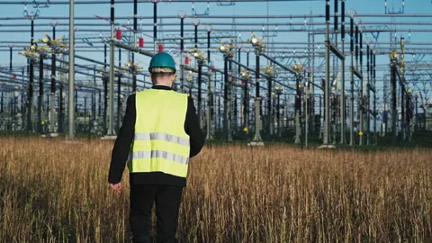 Electric engineer wearing helmet suit and safety vest walking towards substation Stock Footage 171191086