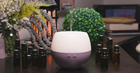 Electric Essential Oils Aroma Diffuser Surrounded by Oil Vials and Flowers Vídeo Stock 111989513