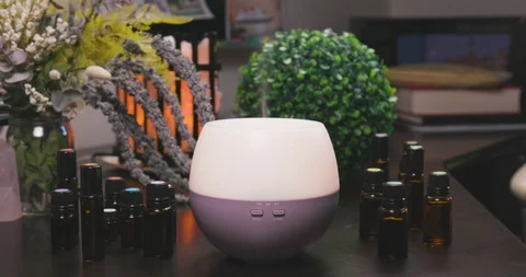 Electric Essential Oils Aroma Diffuser Surrounded by Oil Vials and Flowers Vídeo Stock 111989518