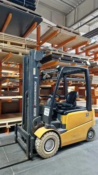 Electric forklift standing between racks with materials Fotos Stock