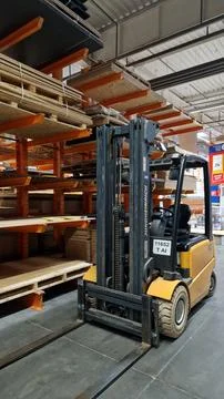 Electric forklift standing between racks with materials Fotos Stock