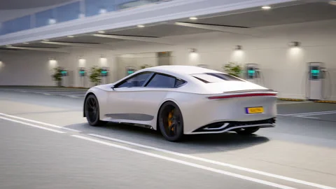 Electric generic modern self driving car driving out of luxury charging park Stock Footage 233591216