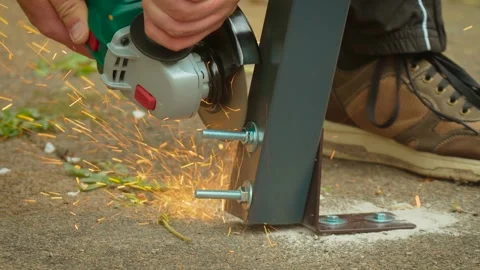 Electric grinder slicing through threaded rod on mounted metal frame with Stock Footage 335144890